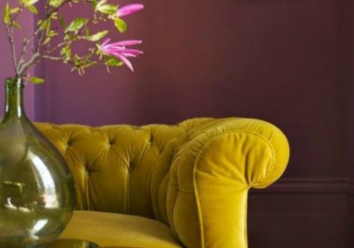 Ροζ τοίχοι, μουσταρδί καναπές και ροζ λουλούδια σε ένα βάζο αρκούν για ένα μοντέρνο αποτέλεσμα στο σαλόνι σας.